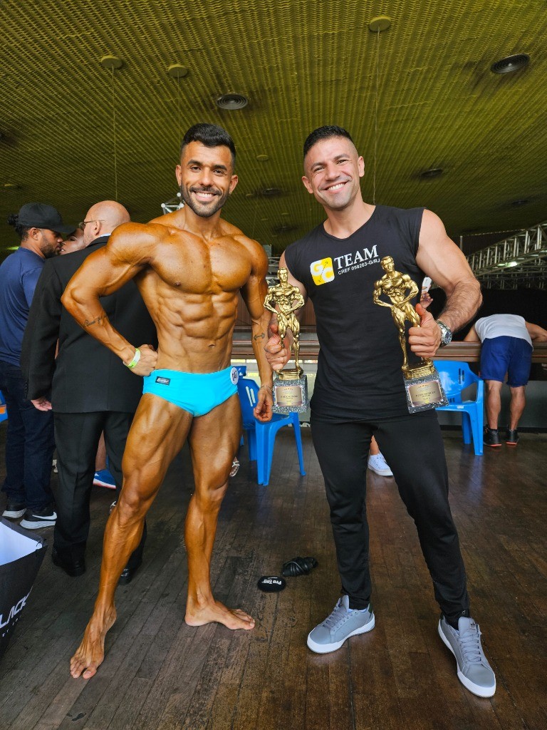 Atleta campeão com troféus ao lado do nutricionista Maurício Gimenez
